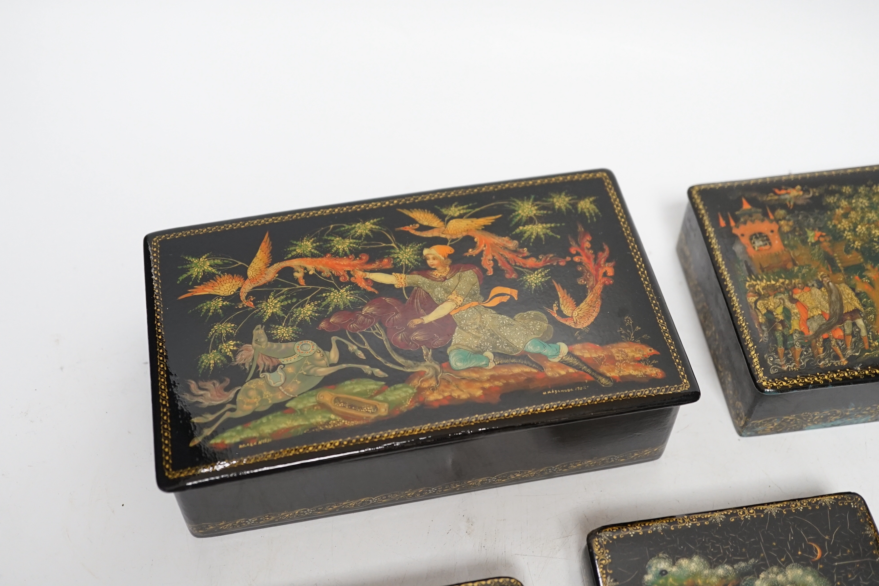 Five Russian Palekh lacquer table boxes, each painted with figures from legend, each signed by the artist, the largest 17 cm wide